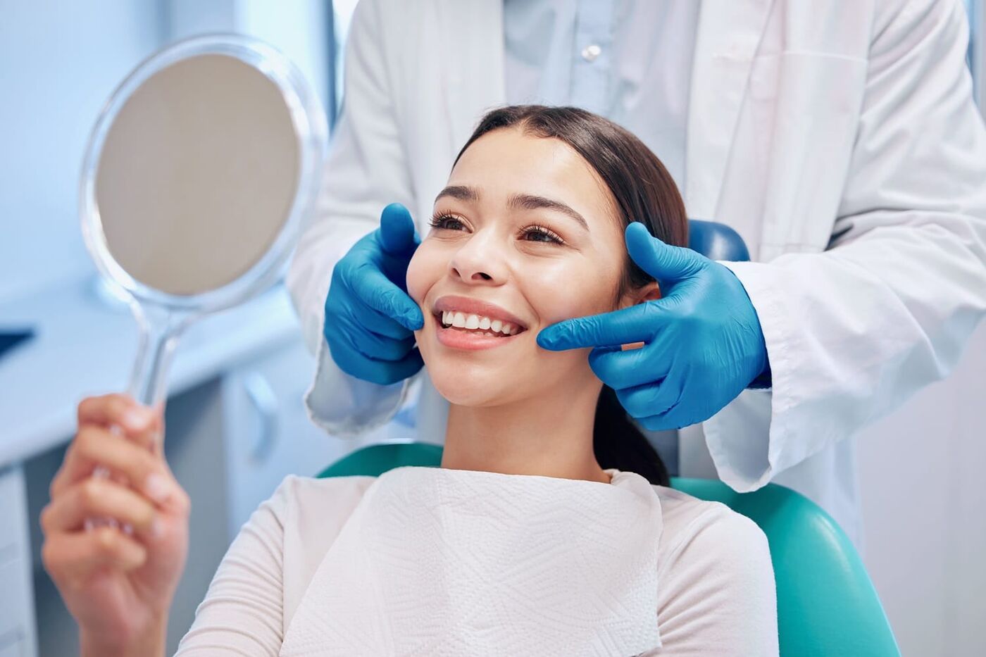 Paciente satisfecha revisando su sonrisa en el consultorio